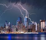 Thrilling lightning storm over a bustling urban skyline at night with stunning reflections on the waterfront.